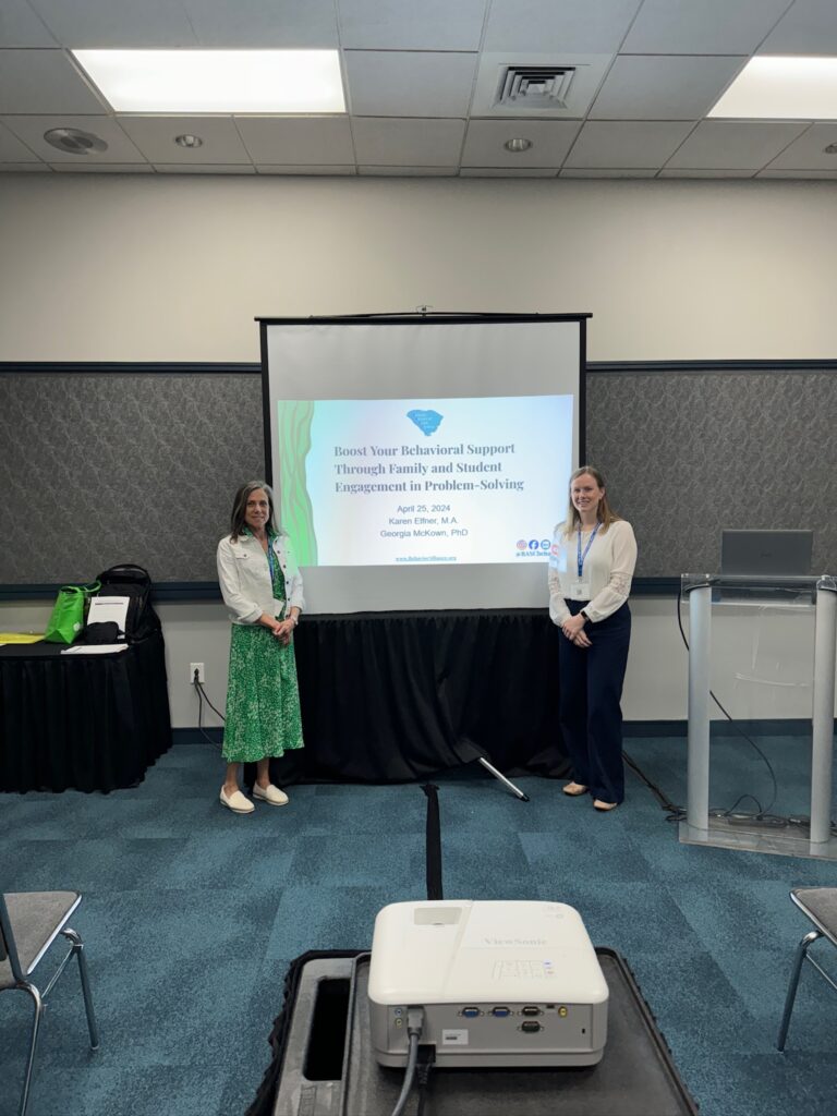 photo of georgia mckown and karen elfner standing in front of their conference presentation slide