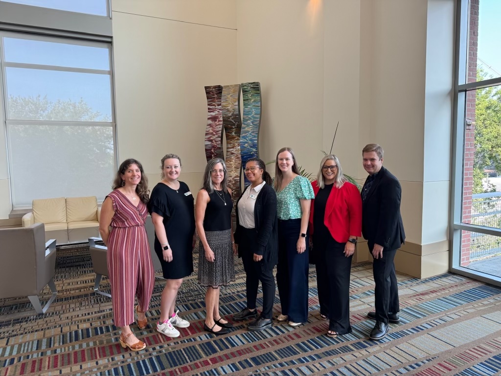 Photo of 7 members of the behavior alliance team, posing in a conference center room